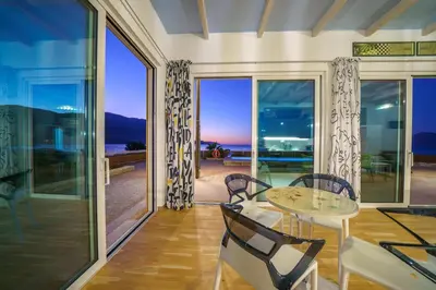 a dining room with glass doors and a table and chairs at Veranda Sul Mare in Gramvousá