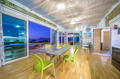 a dining room with a table and green chairs at Veranda Sul Mare in Gramvousá