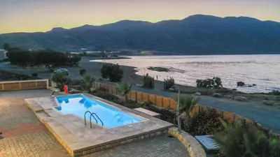 a swimming pool next to a body of water at Veranda Sul Mare in Gramvousá