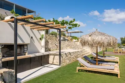a patio with lounge chairs and a thatch umbrella at Luxury Villa Olivenest with Private Heated Pool, Hot Tub & Sauna in Chania Town