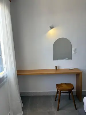 a dressing table with a mirror and a stool at Nikolas Rooms in Loutro