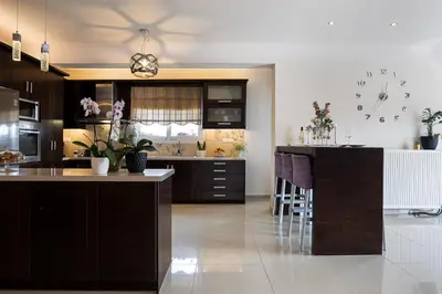 a kitchen with brown cabinets and a bar with stools at SI-EL Villa in Vryses