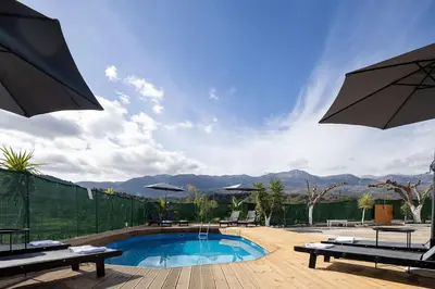 a swimming pool with umbrellas on a wooden deck at SI-EL Villa in Vryses