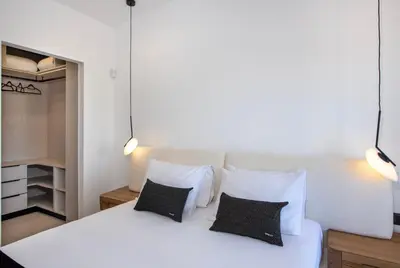 a bedroom with a white bed with two black pillows at Ethernal Luxury Maisonette-Next to the sea in Kamisianá
