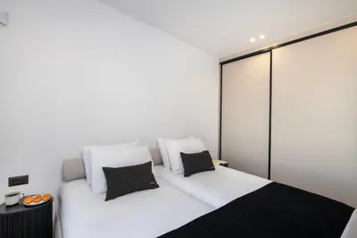 a bedroom with a white bed with black and white pillows at Ethernal Luxury Maisonette-Next to the sea in Kamisianá