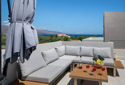 a white couch on a patio with a table and an umbrella at Ethernal Luxury Maisonette-Next to the sea in Kamisianá