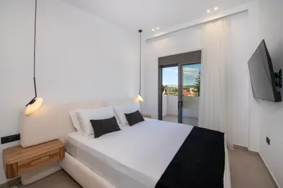 a white bedroom with a large bed and a television at Ethernal Luxury Maisonette-Next to the sea in Kamisianá