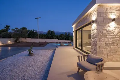 a stone house with a bench and a swimming pool at Villa Zen in Alikianós