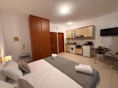 a bedroom with a large white bed and a kitchen at Onar-estia in Chania Town