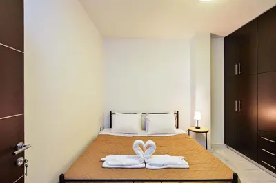 a bedroom with a bed with two white slippers at Arieldine Luxury Apartment in Chania Town
