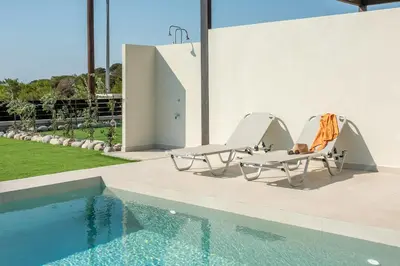 a couple of chairs sitting next to a swimming pool at Elafonisi Pearl in Elafonisi