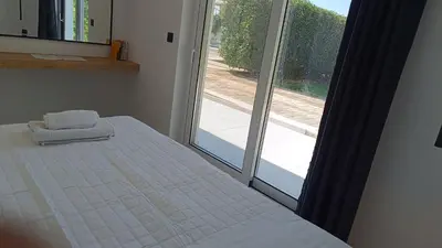 a bedroom with a bed next to a large window at Myrto Villa heated pool in Kato Daratso
