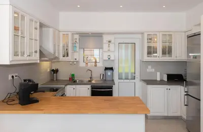 a kitchen with white cabinets and a wooden counter top at Myrto Villa heated pool in Kato Daratso