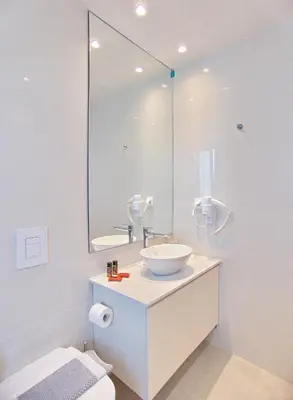 a white bathroom with a sink and a mirror at Melina Apartments Sea & City in Chania Town