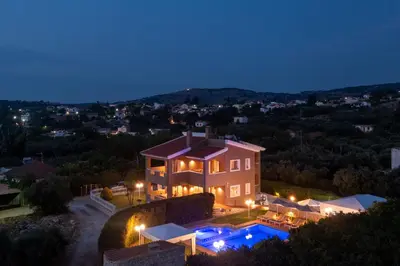 a house with a swimming pool at night at Villa Clio, with Mountain view in Arménoi