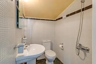 a white bathroom with a sink and a toilet at Villa Clio, with Mountain view in Arménoi