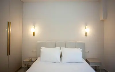 a white bed with two white pillows and two lights at Maira City House in Chania Town