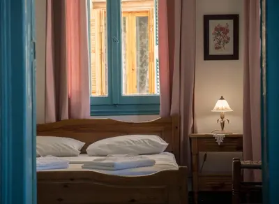 a bedroom with a bed with a window and a lamp at Pension Nora in Chania Town