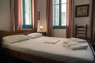 a bed with two towels on it with two windows at Pension Nora in Chania Town