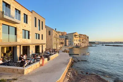a group of people sitting at a restaurant next to the water at Artemis Luxury Home in Chania Town