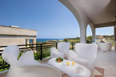 a balcony with white chairs and a view of the ocean at Nektar Luxury Apartment in Stalos