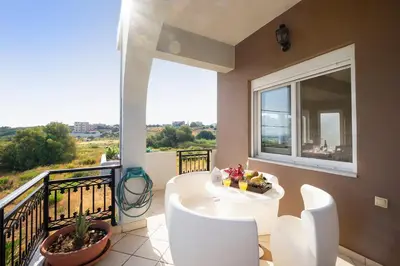 a balcony with a white table and chairs and a window at Nektar Luxury Apartment in Stalos