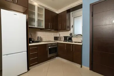 a kitchen with wooden cabinets and a white refrigerator at Zen City Beach Apartment in Chania Town