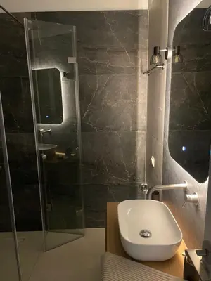 a bathroom with a sink and a glass shower at Nea Chora seaside suites in Chania Town