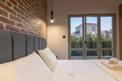 a bedroom with a white bed and a brick wall at Edward Luxury Suites in Chania Town
