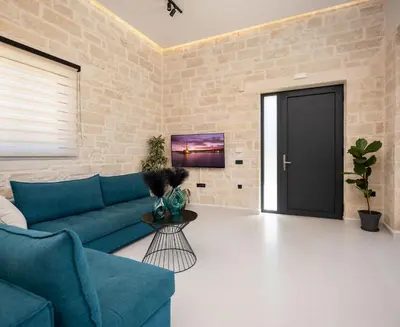 a living room with a blue couch and a brick wall at PanStel - Villa Solene with private pool in Ayiá