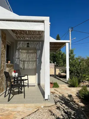 a patio with a table and a white pergola at Villa Karneios in Tavronitis