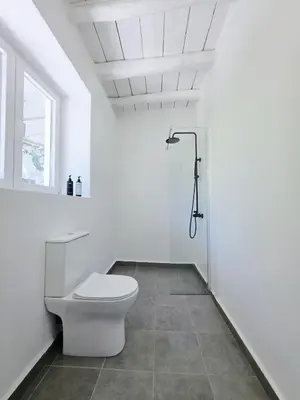 a white bathroom with a toilet and a window at Suites with Shared Garden Sougia in Moní
