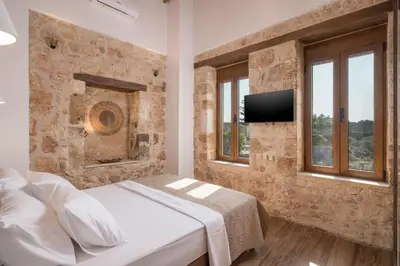 a bedroom with a stone wall with a bed and a tv at Stella's Traditional House Near the City in SFakianalíon