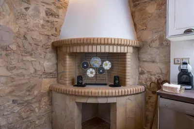 a fireplace in a kitchen with a stone wall at Stella's Traditional House Near the City in SFakianalíon