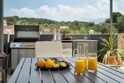 a table with a plate of fruit and two glasses of orange juice at Echoes of Prinos in Metókhion Yianítsari