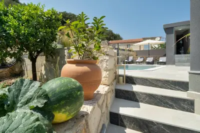 a retaining wall with fruits and vegetables next to a pool at Echoes of Prinos in Metókhion Yianítsari