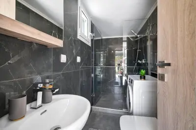 a bathroom with a white sink and a shower at Echoes of Prinos in Metókhion Yianítsari