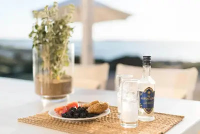 a bottle of wine and a plate of food on a table at Falasarna Seafront House I 50m to the Beach in Kavoúsion