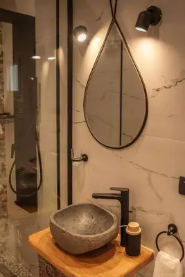 a bathroom with a stone sink and a mirror at SUITEArT 1 Stylish apartment in Chania Town