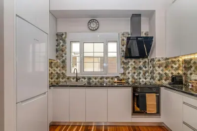 a kitchen with white cabinets and a clock on the wall at SUITEArT 1 Stylish apartment in Chania Town