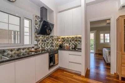 a kitchen with white cabinets and a tv on the wall at SUITEArT 1 Stylish apartment in Chania Town