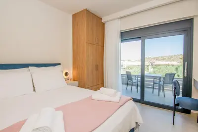 a bedroom with a bed and a balcony with a table at Katakis Afroditi-Athina in Agios Onoufrios