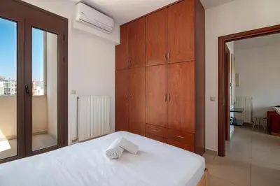 a bedroom with a white bed and wooden cabinets at Light House Chania - 5 Min to Beach and Free Parking in Chania Town