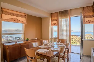 a dining room with a table and chairs and windows at Elysian Bayview Souda Bay Panorama Chania in Zakhariás