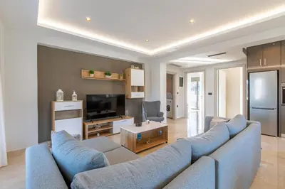 a living room with a blue couch and a television at Neaira Apartments in Vatólakkos