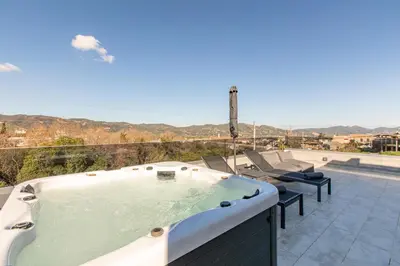 a jacuzzi tub on a patio with chairs at Neaira Apartments in Vatólakkos