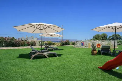 two chairs and two umbrellas on the grass at New Beachfront villa Six Stars in Chania,close to the beach & amenities in Kamisianá