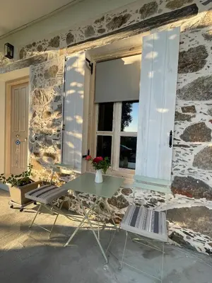 a table and chairs in front of a stone wall at Armela in Áyioi Theódhoroi