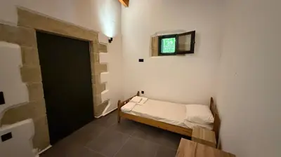 a small bedroom with a bed and a tv on the wall at Stone House Experience in Voúvai