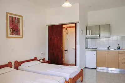 a bedroom with two beds and a small kitchen at Panos Appartments in Palaiochóra